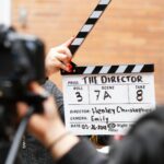 Close-up of film clapperboard in action with camera filming a take on set.
