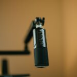 Close-up of a studio microphone setup with a boom arm in warm lighting.