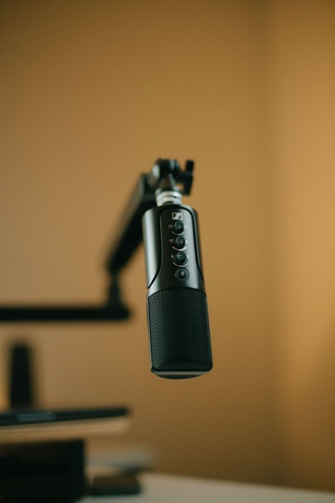 Close-up of a studio microphone setup with a boom arm in warm lighting.
