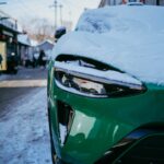 Green car covered in snow on a street