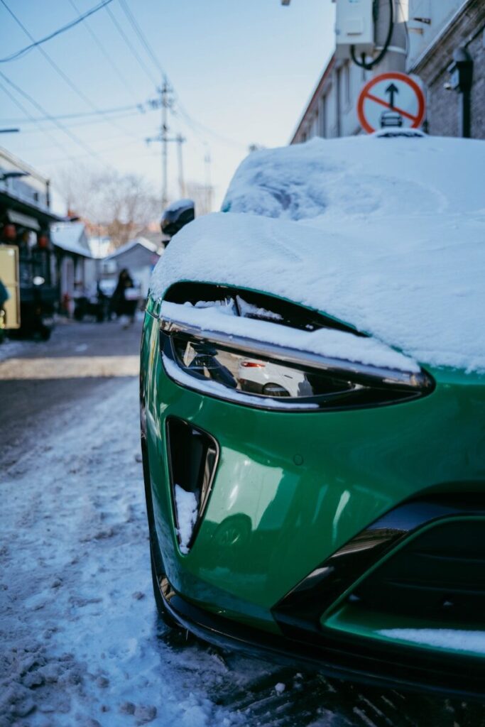 Green car covered in snow on a street